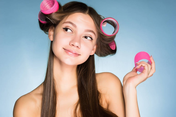 cute young girl thinks about beauty, on her head big pink hair curlers - Foto, Bild
