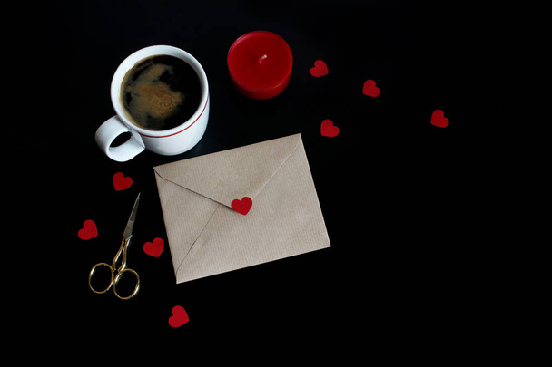 Valentines day or wedding mockup scene with cup of coffee, envelope, paper hearts confetti, red candle, golden scissors on black background. Love concept. Flat lay, top view. Empty space for your text - 写真・画像