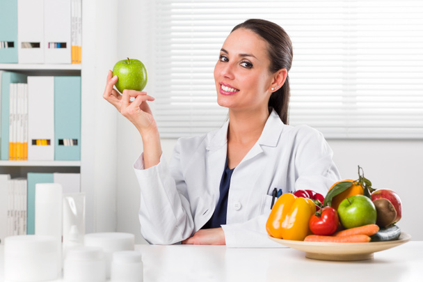  Женщина-диетолог держит зеленое яблоко
 - Фото, изображение