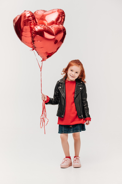 adorable little girl with balloons in shape of hearts isolated on grey - Foto, Imagem