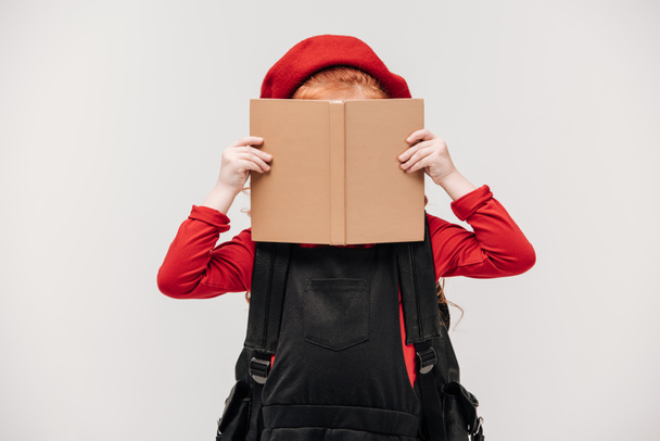 little schoolgirl covering face with book isolated on grey - Foto, immagini
