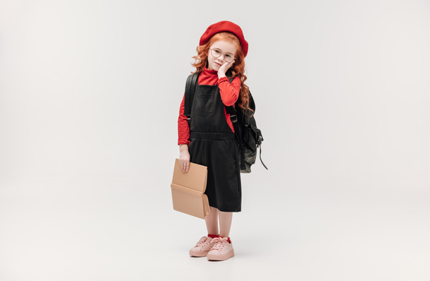 adorable little schoolgirl with backpack and big book isolated on grey - Photo, Image
