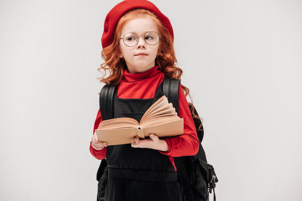 thoughtful little schoolgirl with book isolated on grey - Photo, Image