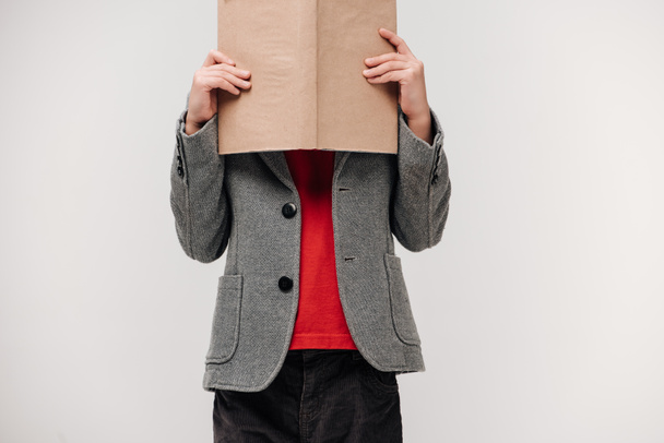 little schoolboy covering face with book isolated on grey - Foto, Imagem