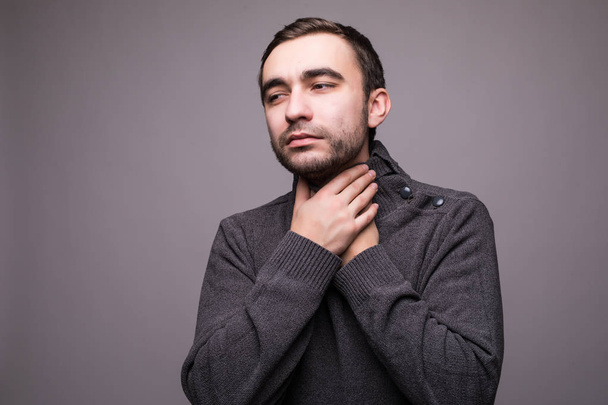 junger Mann mit Halsschmerzen und Berührungen am Hals vor hellgrauem Hintergrund. - Foto, Bild