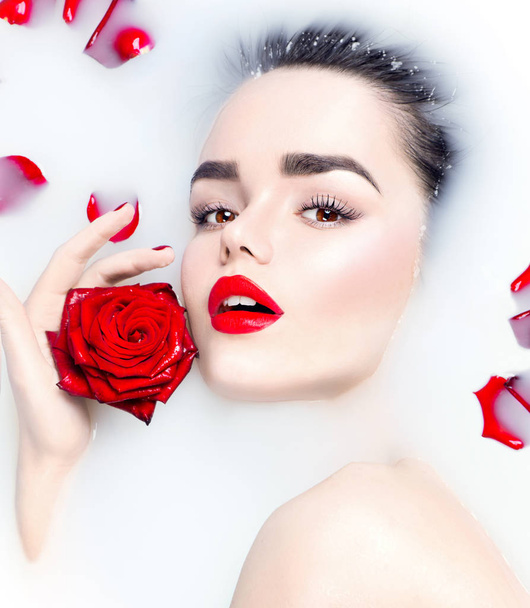  young model with red lips and red rose flower in milk bath - Zdjęcie, obraz