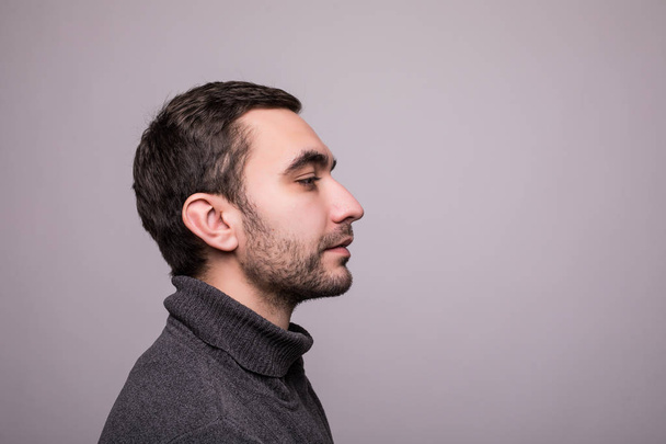 Side view portrait of thinking stylish young man looking away on gray background - 写真・画像