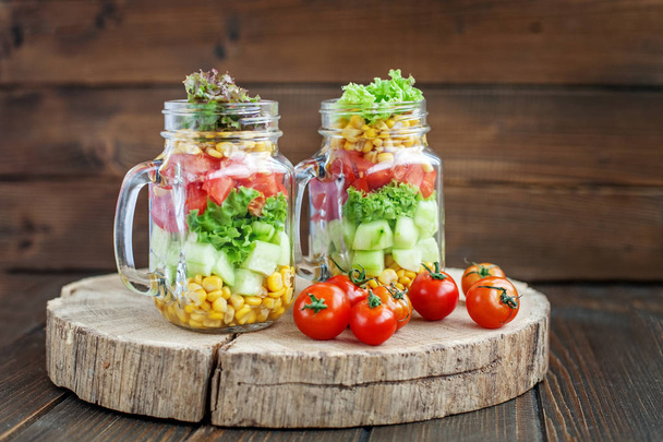 野菜サラダ、ミニトマト 2 つのガラスの瓶.  - 写真・画像