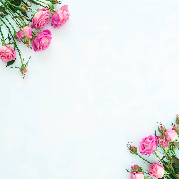 Blumenmuster mit rosa Rosen auf hellblauem Hintergrund. flache Lage, Draufsicht.  - Foto, Bild