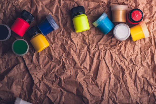 colorful watercolor paint bottles for textile on crumpled kraft paper surface - Фото, изображение