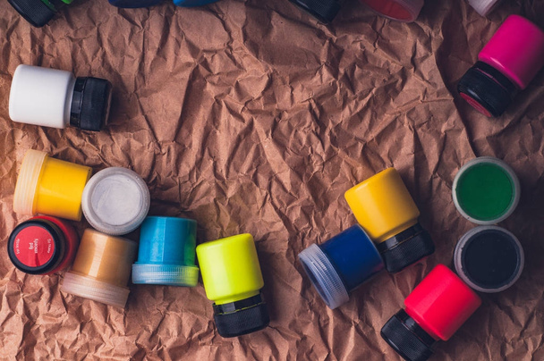 colorful drawing paint bottles for textile on crumpled kraft paper surface - Fotó, kép