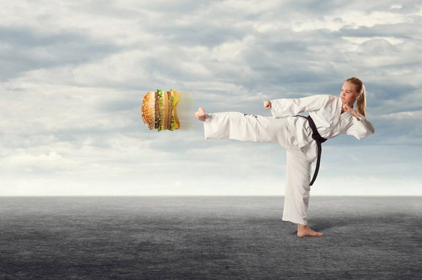 La mujer karate pateando la hamburguesa. El concepto de alimentación saludable
. - Foto, imagen