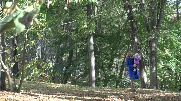 Νέοι όμορφη μητέρα περπατώντας με το μωρό της σε ένα Φθινοπωρινό πάρκο. 4k - Πλάνα, βίντεο