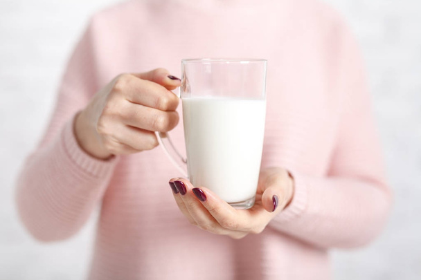 the woman is holding a glass mug of milk - Fotó, kép