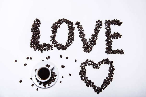 Осінній, осінній лист клена з гарячою чашкою кави та написом кохання кавових зерен на фоні дерев'яного столу. Сезонна, ранкова кава, недільний відпочинок та концепція натюрморту
. - Фото, зображення