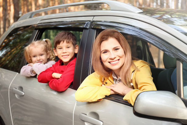 Mujer feliz con sus hijos pequeños en coche en el día soleado
 - Foto, imagen
