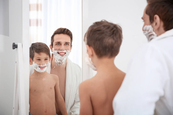 Vader en zijn zoontje scheren in badkamer - Foto, afbeelding