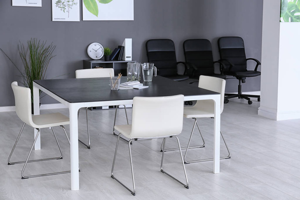 Современный офисный интерьер со столом и белыми стульями
 - Фото, изображение