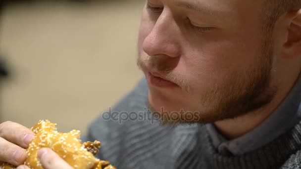 kafede oturan hamburger yeme genç hipster adam - Video, Çekim