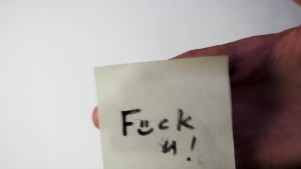 Opschrift fuck you op de sticker. Opmerking fuck you op een stuk papier op het glas, het concept van agressie - Video
