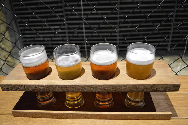 τέσσερα ποτήρια μπύρας σε μια ξύλινη βάση - Φωτογραφία, εικόνα