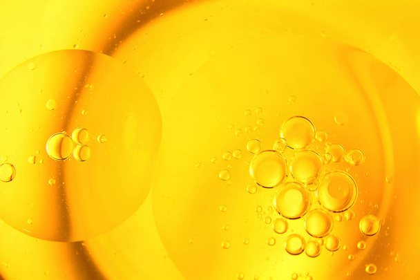 gelbe und orangefarbene Blasen und Tropfen Öl in Wasser, Olivenöl Küche Hintergrund zum Kochen. - Foto, Bild
