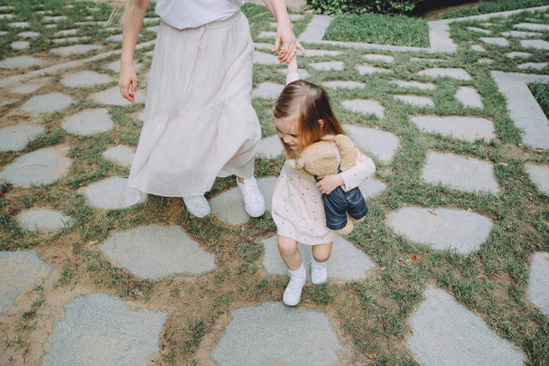 緑の夏の庭を歩いて彼女の愛らしい小さな娘と母の写真をトリミング - 写真・画像