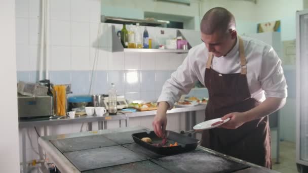 Joven cocinero jefe con uniforme preparando una carne
 - Metraje, vídeo