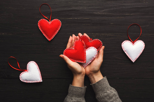 Valentine dag achtergrond, kussen harten in vrouwelijke handen - Foto, afbeelding