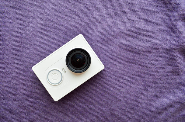 Mor bir arka plan üzerinde büyük bir siyah lens ile beyaz eylem fotoğraf makinesi - Fotoğraf, Görsel
