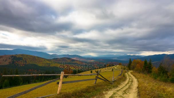 Jesienią. Fantastyczne góry krajobraz z polnej drodze, Las, kolorowe drzewa, szybko puszyste chmury i cienie. Timelapse. - Materiał filmowy, wideo