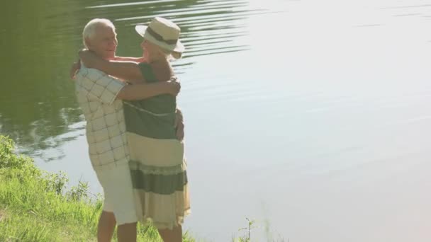 高齢者のカップルが川の近くを抱いて. - 映像、動画