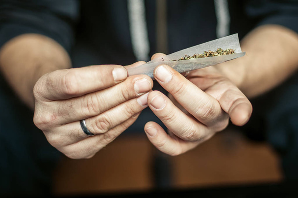 Preparing and rolling marijuana cannabis joint. Drugs narcotic c - Foto, Bild