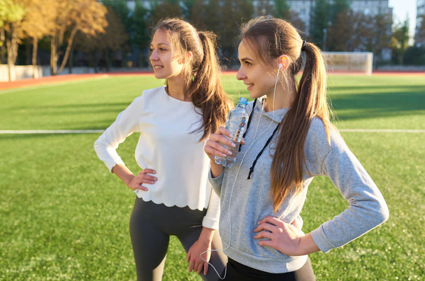 Kaksi urheilu tytöt seisovat ja levätä harjoituksen jälkeen
. - Valokuva, kuva