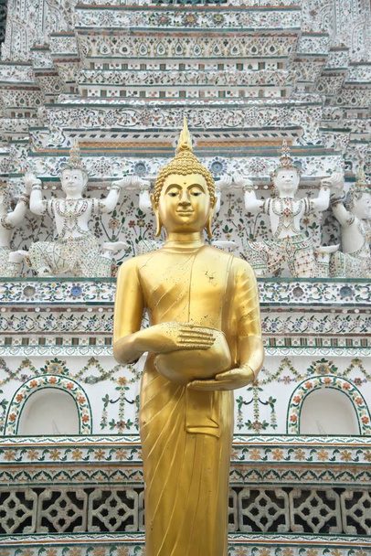 Golden standing Buddha front of the main feature of Wat Arun Ratchawararam Ratworamahawihan ( Temple of Dawn ) is a Buddhist temple in Bangkok , Thailand  is its central prang (Khmer-style tower) which is encrusted with colorful porcelain. - Foto, imagen