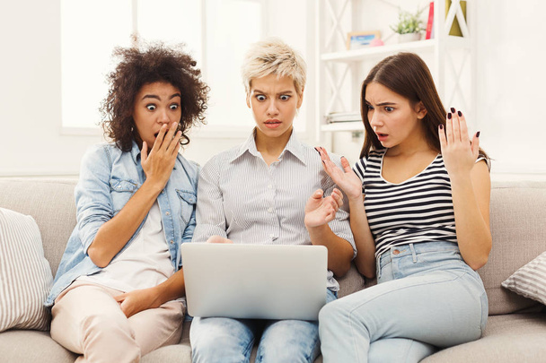 Τρεις όμορφες γυναίκες σοκαρισμένος που χρησιμοποιούν φορητό υπολογιστή στο σπίτι - Φωτογραφία, εικόνα
