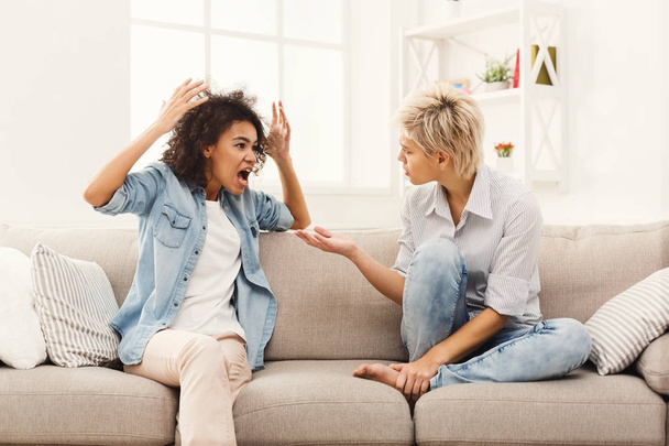 Two female friends sitting on sofa and arguing - Zdjęcie, obraz