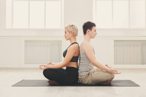 Young couple meditating together, back to back - Photo, image