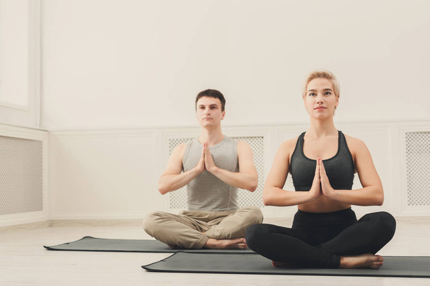 Pareja joven practicando yoga sentada en padmasana
 - Foto, imagen