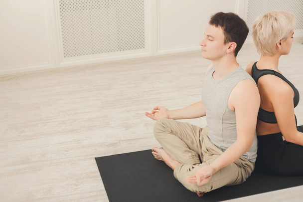Young couple meditating together, back to back - Photo, Image