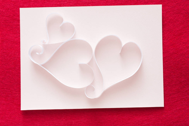 Фон Валентина с бумагой ручной работы формы сердца украшения на белом дерьме бумаги на красном войлоке
 - Фото, изображение