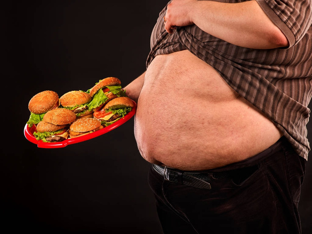Muž břišní tuk s hamberger rychlého občerstvení. Snídaně s nadváhou osoba. - Fotografie, Obrázek