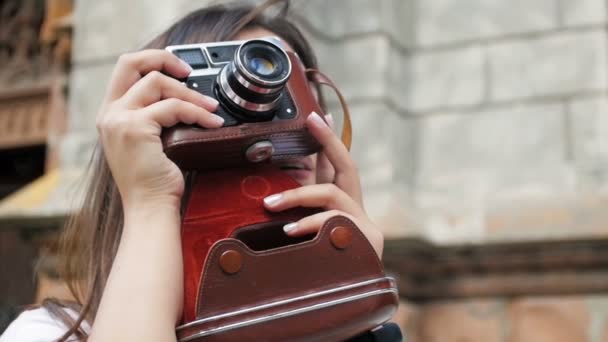 Vértes lassított portréja mosolygó fiatal lány pózol, vintage film fényképezőgép utcában - Felvétel, videó