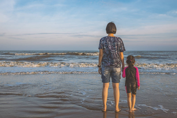 Asian mother holding daughter's hand on the beach - Photo, Image