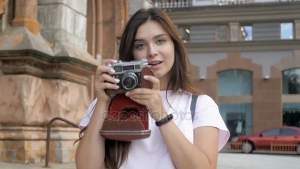 Gülümseyen slow motion video esmer turist kız yürüyüş ve eski film kamera ile fotoğraf yapma - Video, Çekim