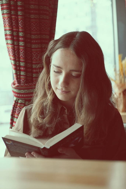 Diligente studentessa legge un libro in un caffè
 - Foto, immagini
