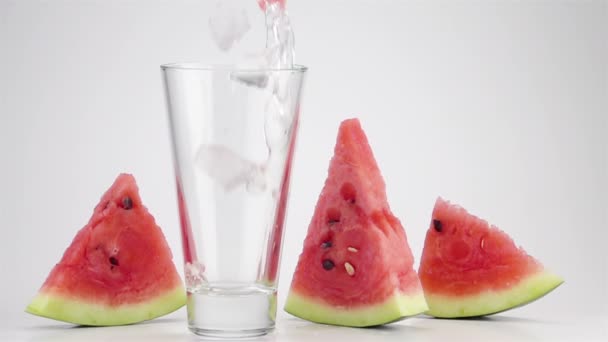 Ömlött a jég és a görögdinnye kockák szódavíz egy pohárba. Super Slow Motion. - Felvétel, videó