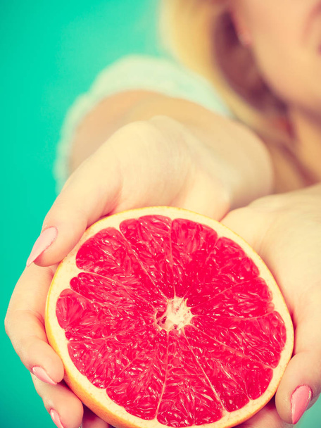 Half of red grapefruit citrus fruit in human hands - Fotoğraf, Görsel