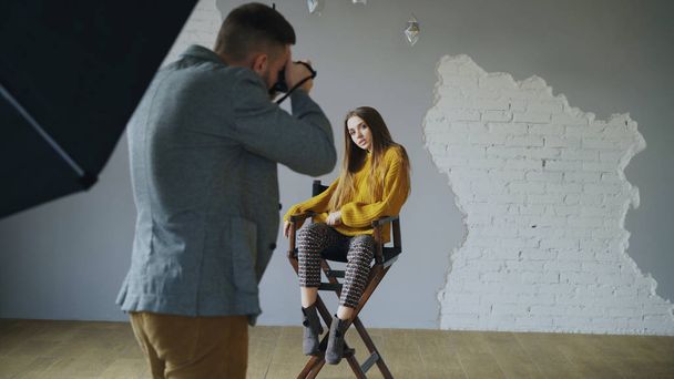 Young beautiful woman model posing for photographer while he is shooting with a digital camera in photo studio indoors - Foto, Bild