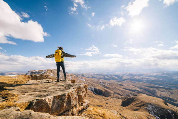 young girl tourist is standing on top of the mountain with open hands - Фото, зображення